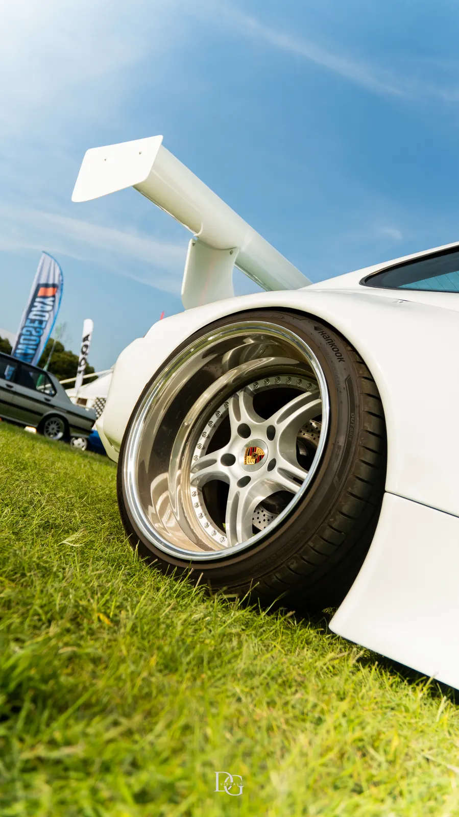 Detalle de llanta y alerón de un Porsche blanco